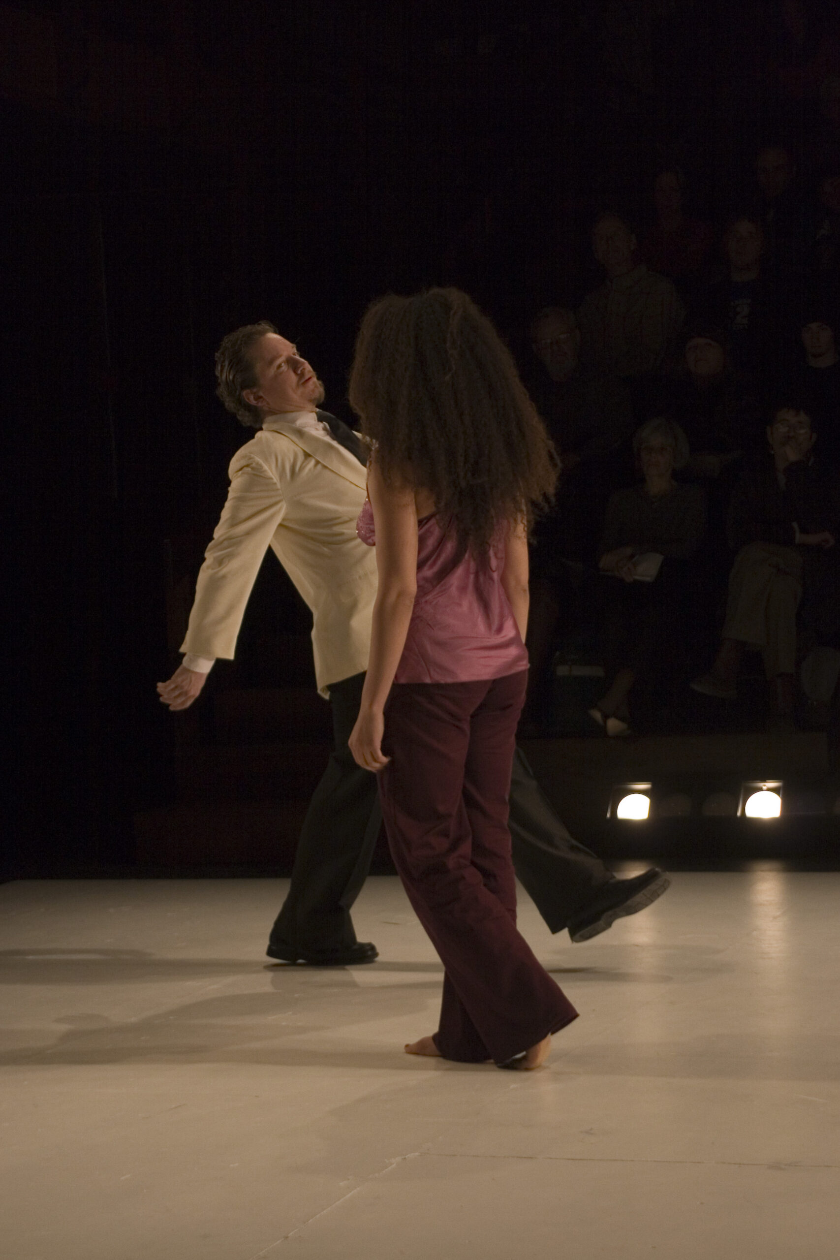 Two performers mid-scene under stage lights